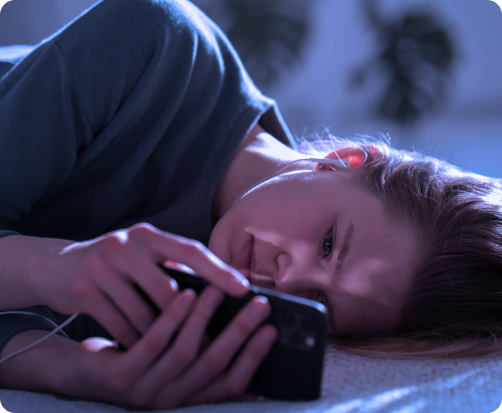 Personne allongée en train d'utiliser un smartphone